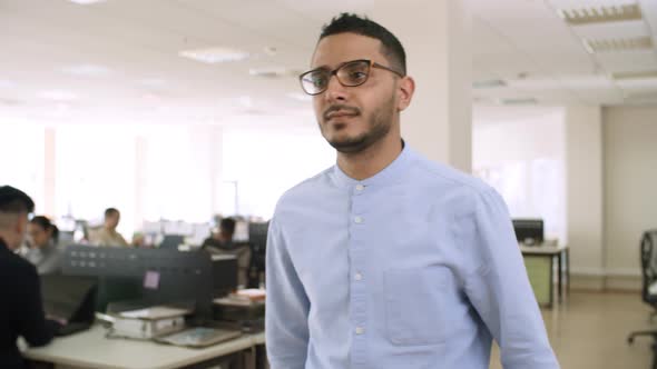 Young Man in Glasses Walking through Office