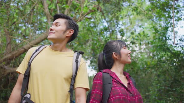 Young Asian man and woman friend traveling in the forest together, walking with happiness and fun.