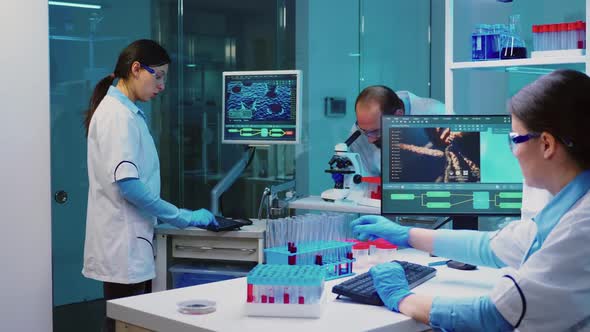 Researcher Using Microscope in Laboratory While Nurse Taking Notes