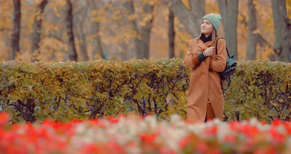 Beautiful Young Girl in a Coat Walking in the Autumn Park