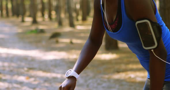 Female jogger checking time on smartwatch in the forest 