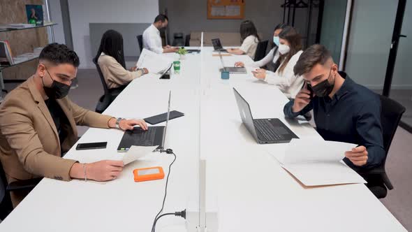 Group of colleagues sitting at table in office and working