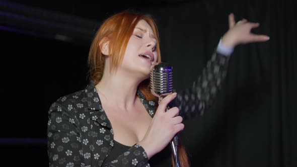 Redhead Young Caucasian Talented Woman Singing with Microphone Performing on Stage Indoors