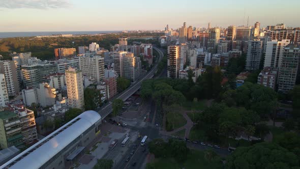 Dolly in flying over train station near park surrounded by Belgrano neighborhood buildings and Rio d