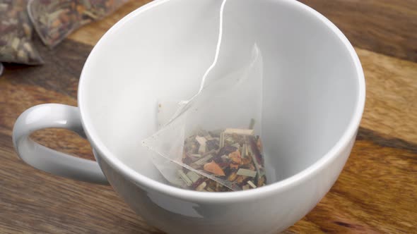 Empty white tea cup with herbal floral aromatic tea bag on old board