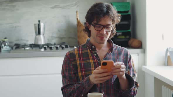 Handsome adult man in a plaid shirt texting on phone