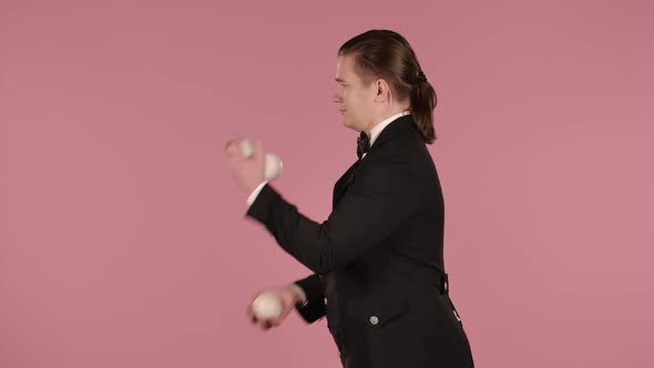 Man Juggler Shows Tricks with White Balls Tossing and Catching Them