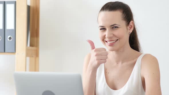 Thumbs Up Gesture By Woman at Work in Office