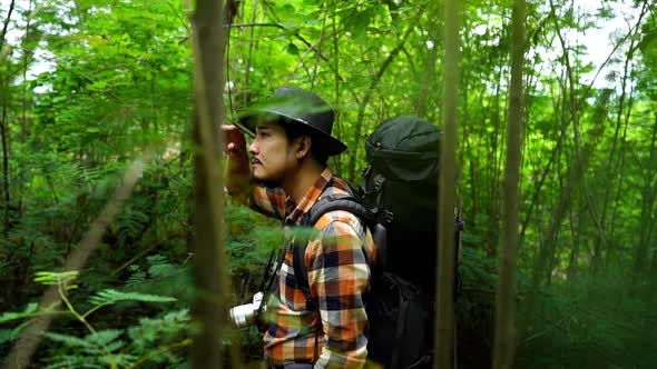 panning shot of tired man traveler with backpack in the natural forest