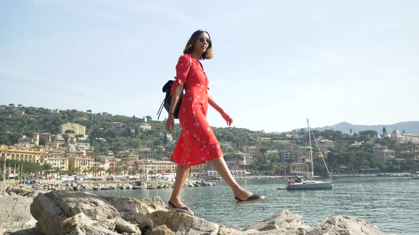 A woman walking in a red dress in a luxury resort town in Italy, Europe.