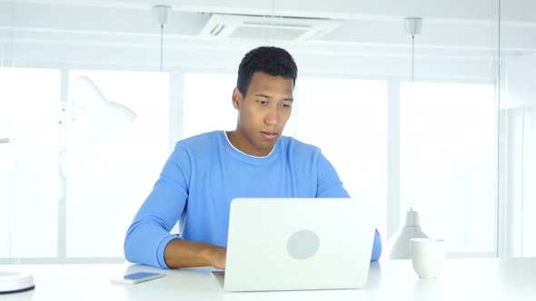 Afro-American Man Thinking and Working on Laptop
