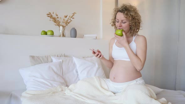 Beautiful Pregnant Woman Using Mobile Phone In Her Bedroom