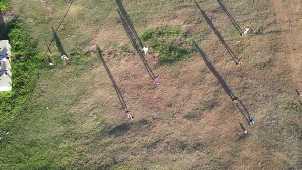 Drone View of Kids Playing Soccer on Field with Shadows Showing