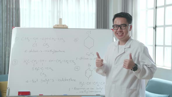 Asian Male Teacher Showing Thumbs Up Gesture And Smiling To Camera While Teaching Chemist At Home