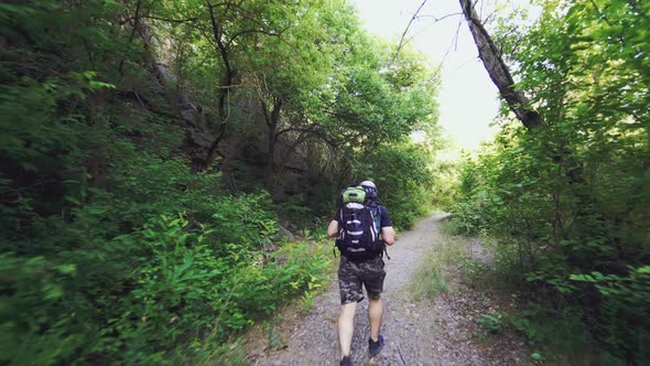 A man with a backpack on his shoulders is climbing up the path