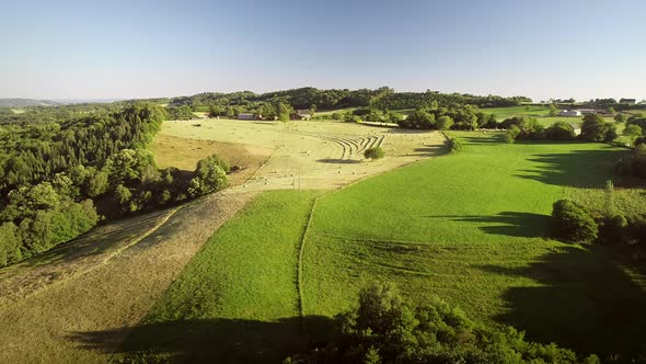 Aerial view of tractor harvesting straw bales in field, Correze, France.