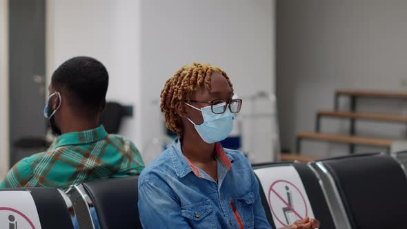 Female Patient with Face Mask Sitting in Waiting Room Area