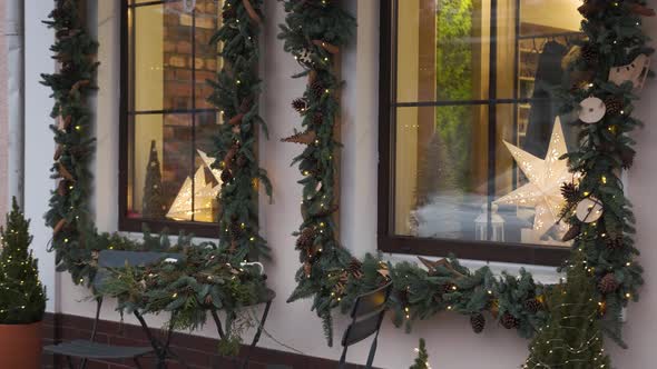 Windows decorated to Christmas with christmas trees fir branches, decorations and garland lights