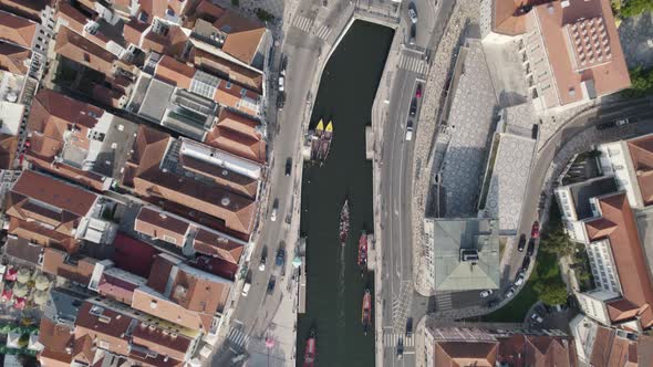 Moliceiros with tourists on busy Ria de Aveiro urban canals. Top down aerial cityscape