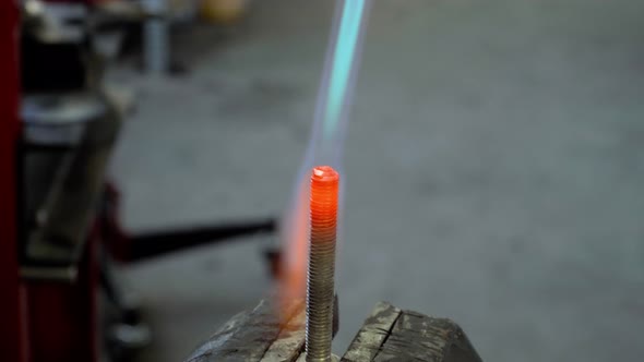 Fire of gas burner heats up red-hot the metal bolt closeup