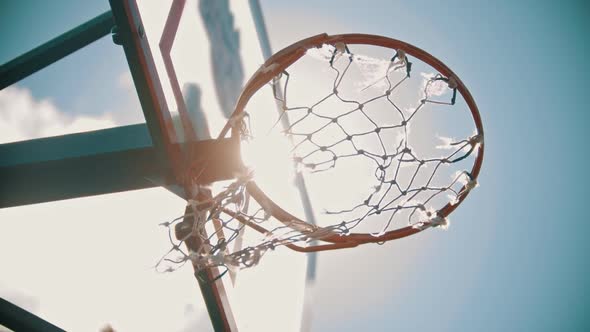 A Basketball Hoop. A Ball Gets in the Target. Bright Sunlight