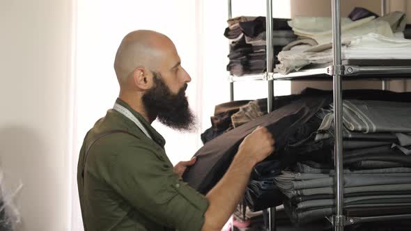 Tailor choosing a fabric from the shelf