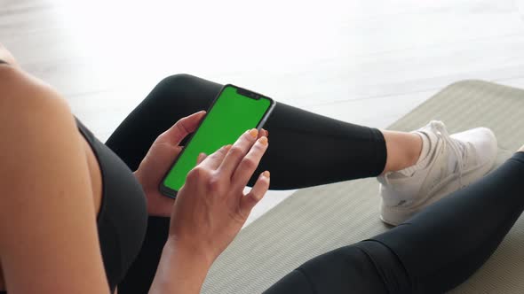 Athletic Woman Holding Smartphone in Fitness Studio Closeup