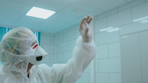Scientist in Protection Suit Holding Covid19 Test Tube on the Light in Lab