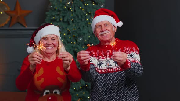 Happy Mature Family Couple in Festive Clothes Waving Sparklers Bengal Lights at Home Christmas Eve