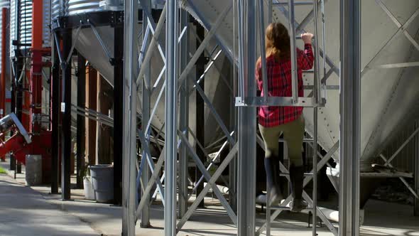 Rear view of caucasian female worker climbing ladder by storage tank 4k