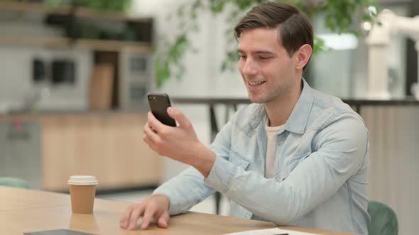 Creative Young Man Using Smartphone at Work