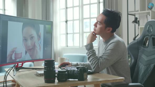 Asian Cameraman Thinking While Using Desktop Computer For Working At Home