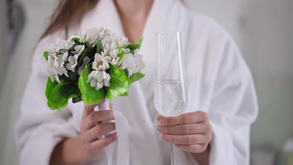 Closeup Bridal Bouquet and Champagne Glass in Slim Female Caucasian Hands