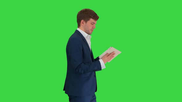 Smiling Businessman Using Digital Tablet While Walking on a Green Screen Chroma Key