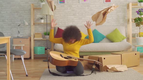 Cheerful African Woman with an Afro Hairstyle Unpacks a New Guitar Slow Mo