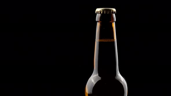 Glass Bottle of Beer Spinning in the Dark on a Black Background