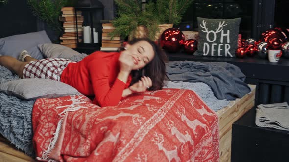 Beautiful woman in red sweater. Happy young woman in bed during Christmas