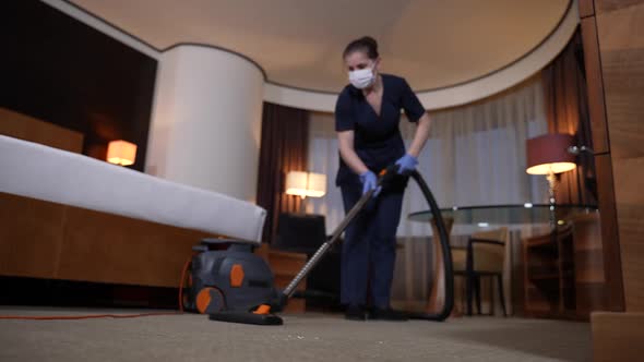 Diligent Housemaid Vacuuming Carpet in Hotel Room