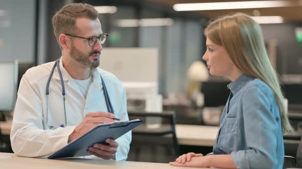 Middle Aged Male Doctor Talking to Female Patient