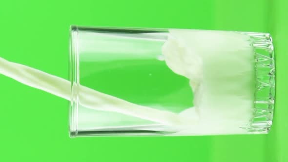 Vertical Video Milk Pouring Into Glass Close Up Isolated on Light Green Background Slow Motion