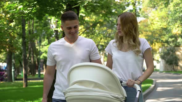 Loving Parents Walking in Sunny Park with Baby Stroller
