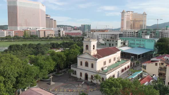 Drone orbit shot of church in Taipa Village with casinos in background