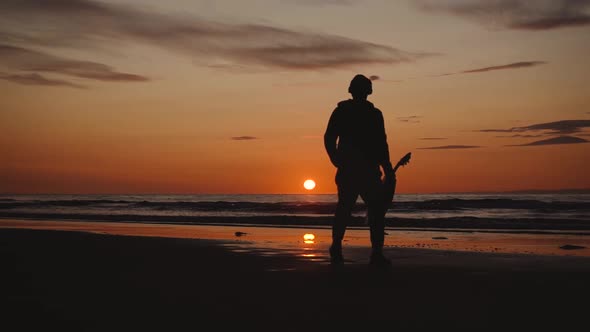 Man running with guitar in back sand beach at sunset. Beautiful, moody shots from the Sony a7iii.