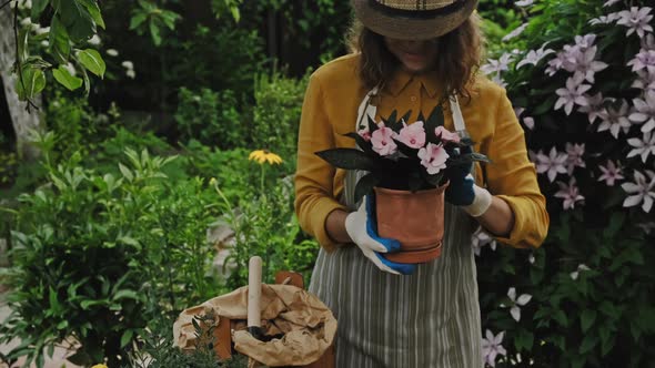 Female Gardener Sniffing Potted Balsam Plant in Backyard Garden in Summer