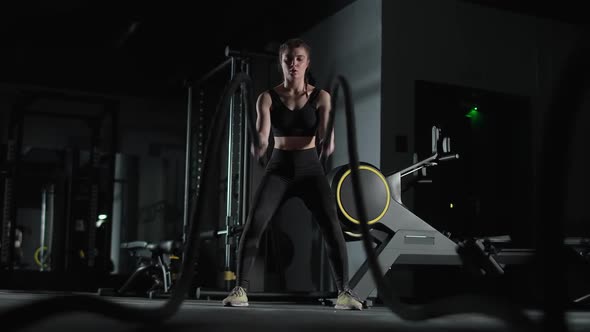 Caucasian Female Fighter Performs Exercises with Battle Ropes Endurance Training in the Gym Slow