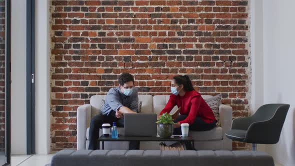 Man and woman wearing face masks working together in office