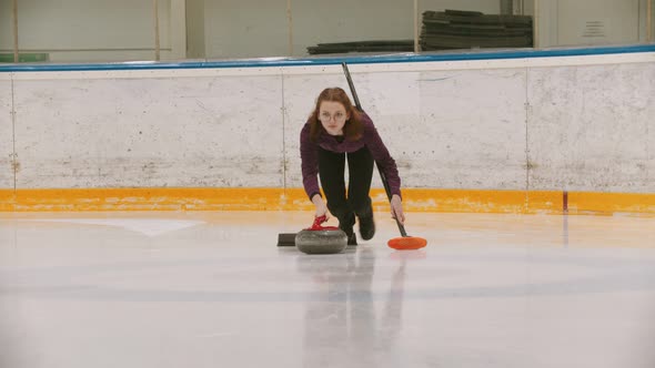 Curling - a Woman in Glasses Skating on the Ice Field and Leading a Granite Stone