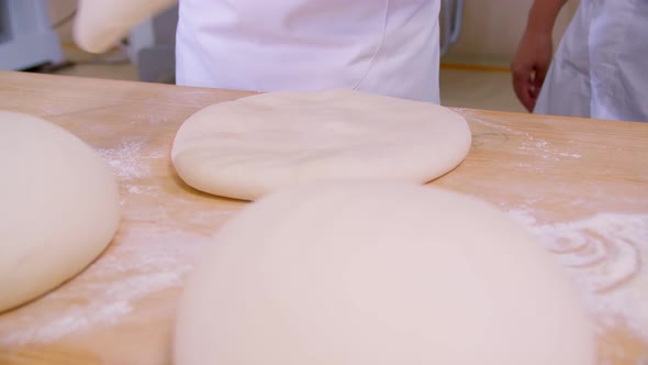 Closeup of Dough Kneaded By Baker on a Wooden Board Sprinkled with Flour