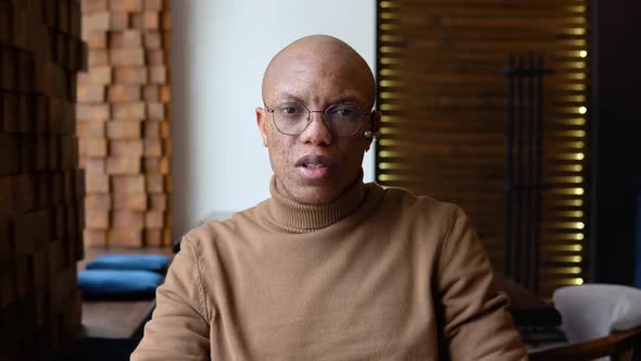 An African American Man is Negotiating Remotely Through a Video Chat Looking at the Camera