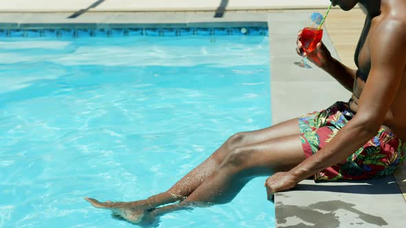 Low section of black man drinking cocktail drink near swimming pool 4k